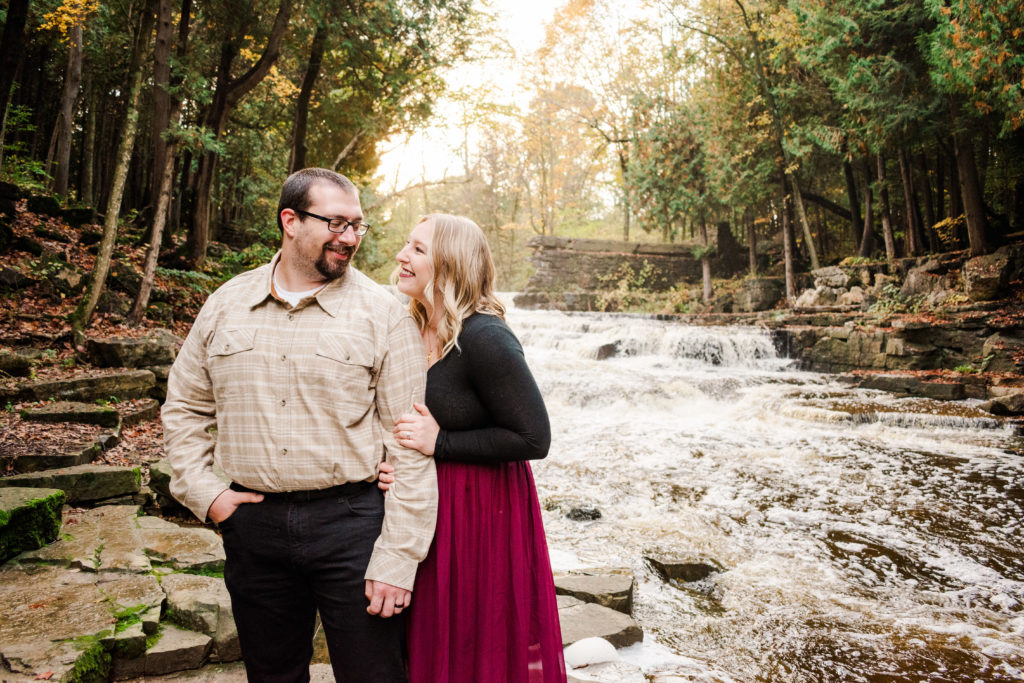 Girl smiling at Guy in front of waterfall during Fall