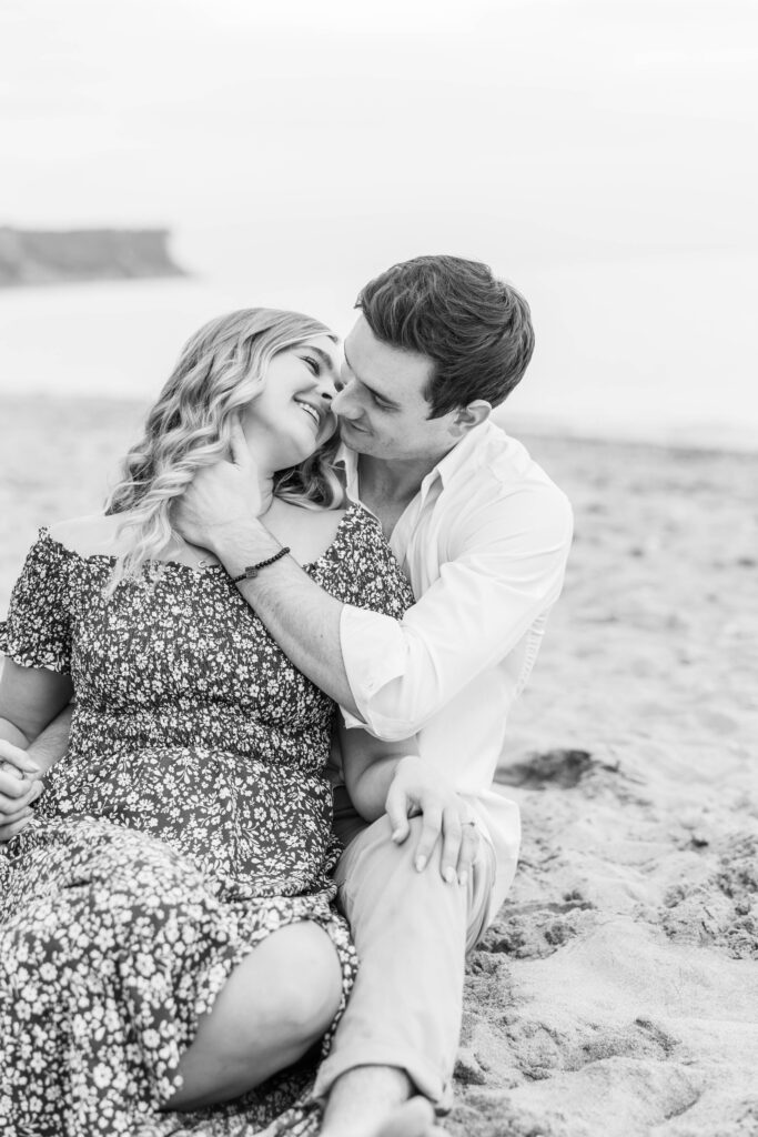 Engaged couple snuggling on the beach on Lake Michigan. 
