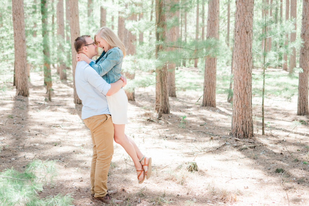 Engaged couple picking up girl and laughing in evergreen forest