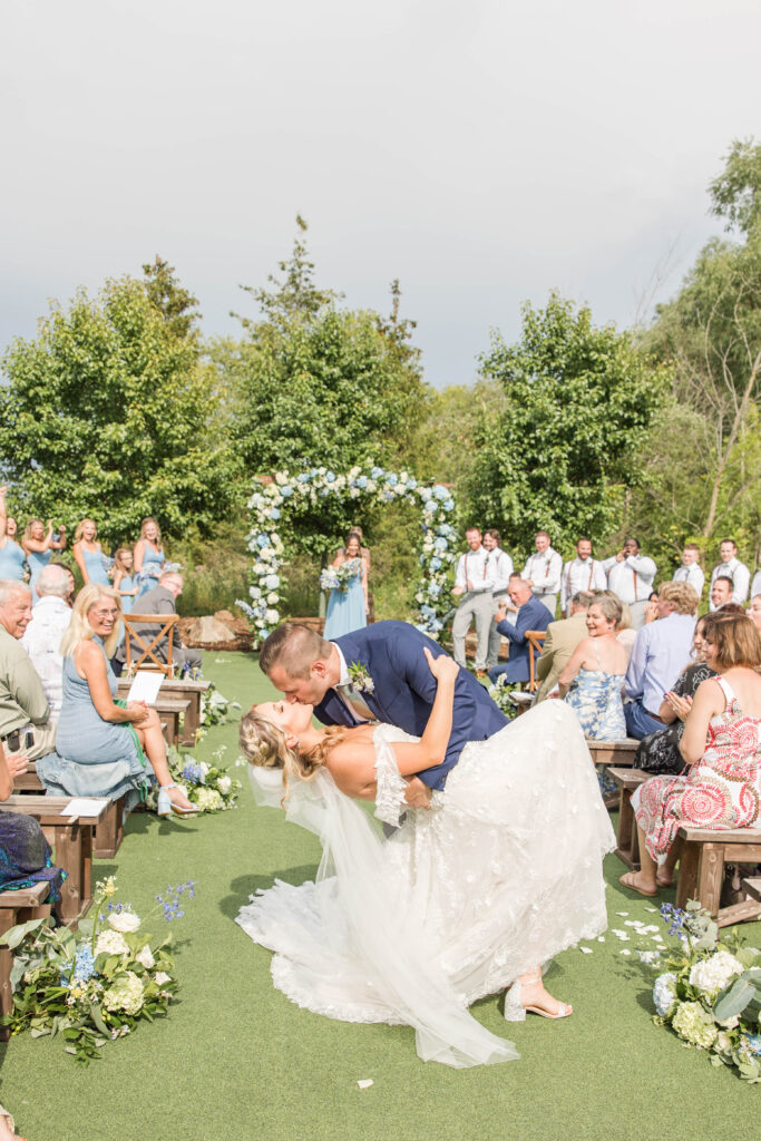 Bride and groom dip kiss walking down the aisle.  