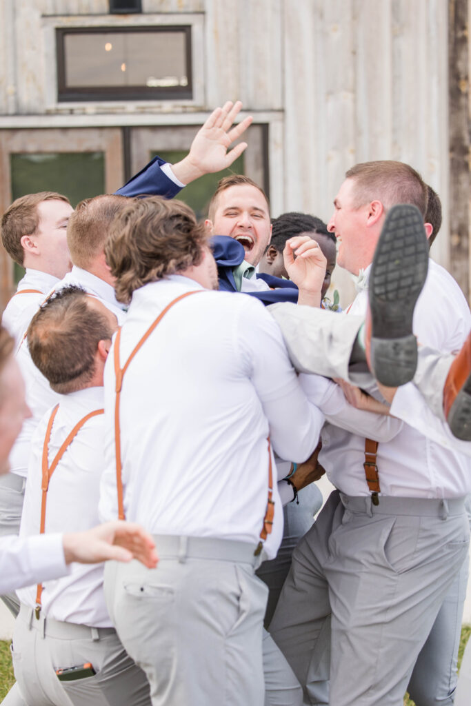 Groomsmen lifting up groom. 