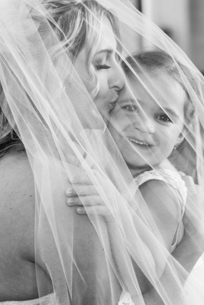 Bride and flower girl under bridal veil. 