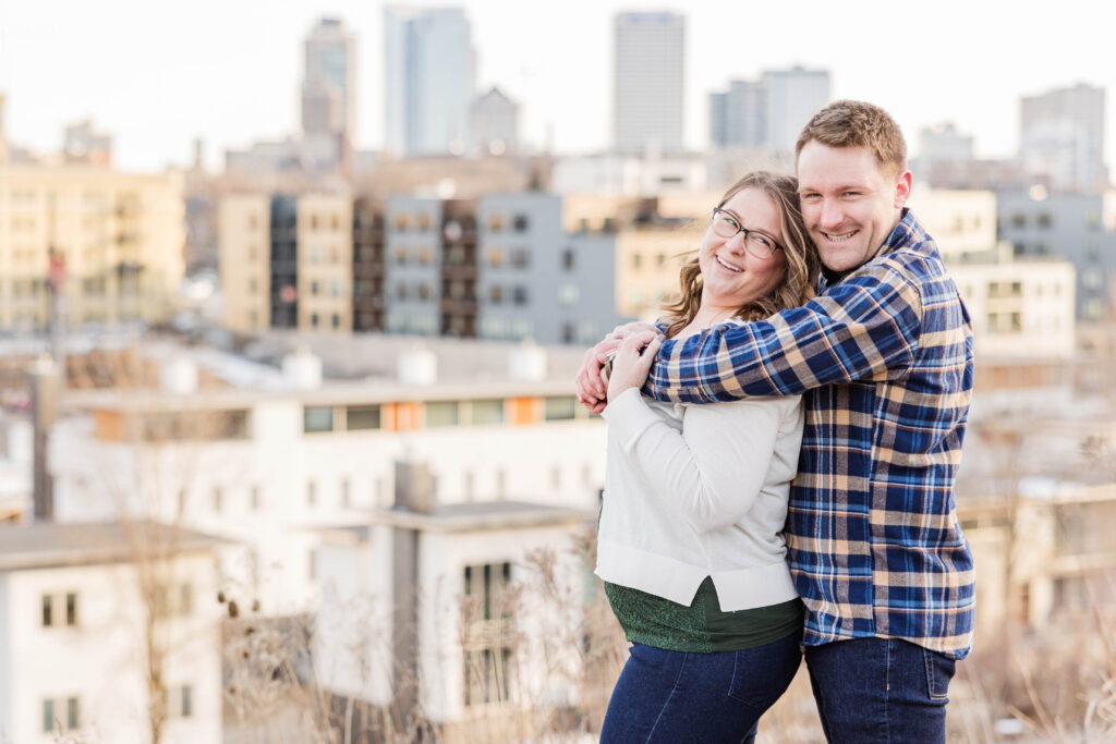 Engaged couple laughing in front of the Milwaukee skyline in Wisconsin. 