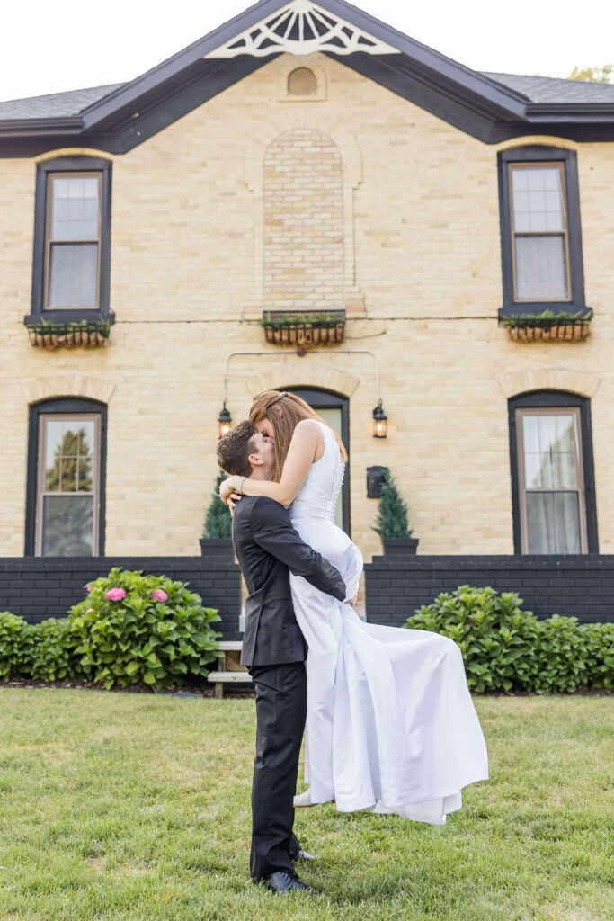 Bride and groom lift kiss in front of the Bowery in Wisconsin.