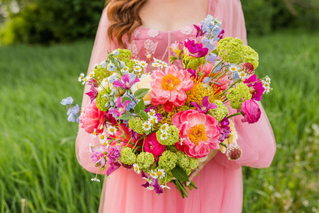 Stunning pink floral bouquet with pops of purple and green designed by Flora Elements with pink ball gown with floral details at Fete of Wales in Wisconsin. 