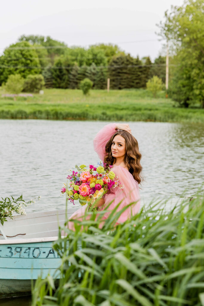 Bride in pink wedding gown in a blue paddle boat on a pond in Waukesha, Wisconsin.