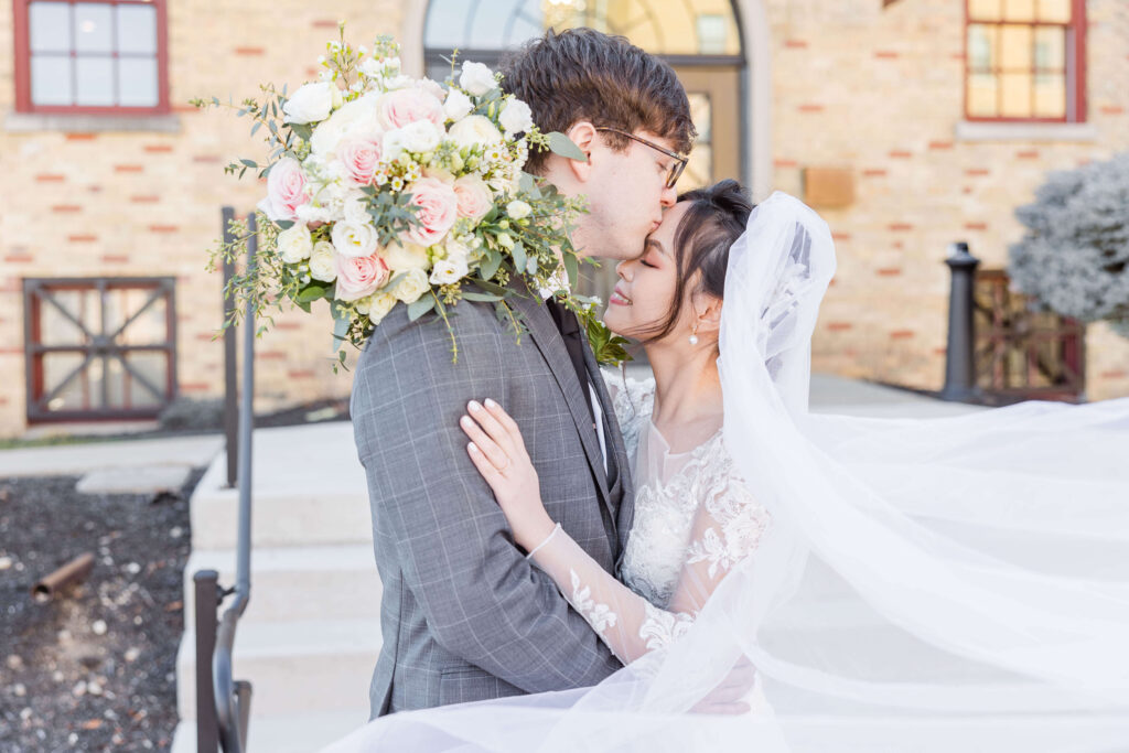 Groom kissing bride's forehead.