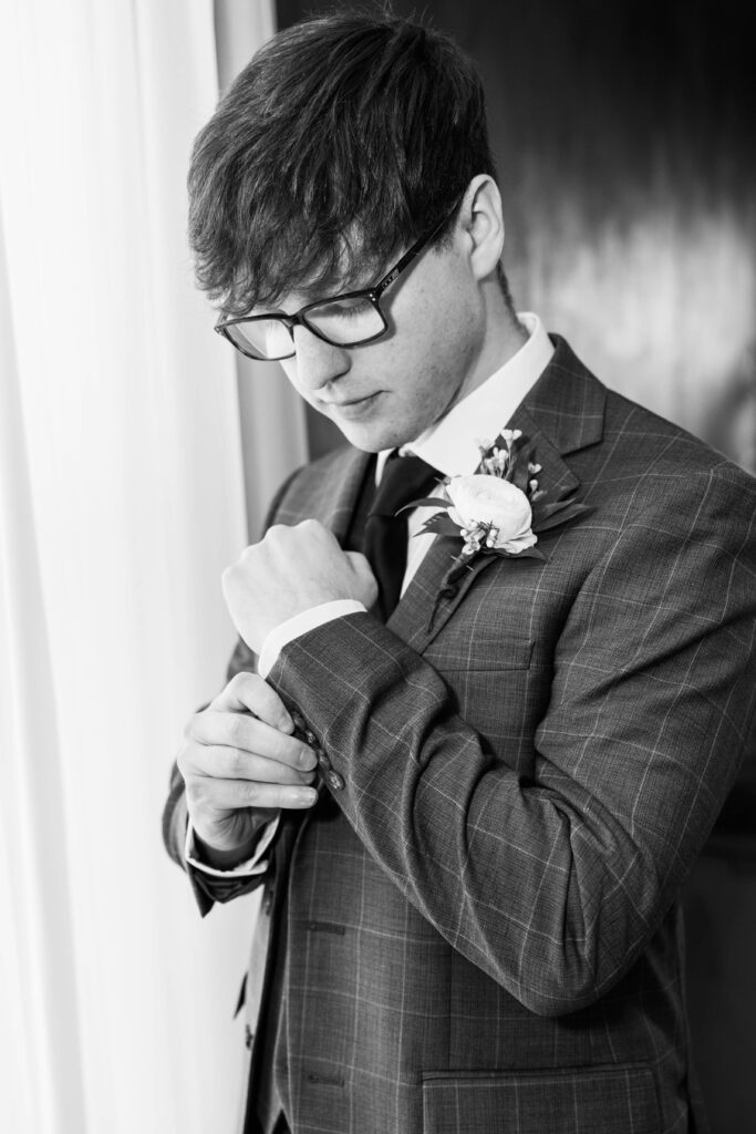 Groom adjusting his shirt on his wedding day.