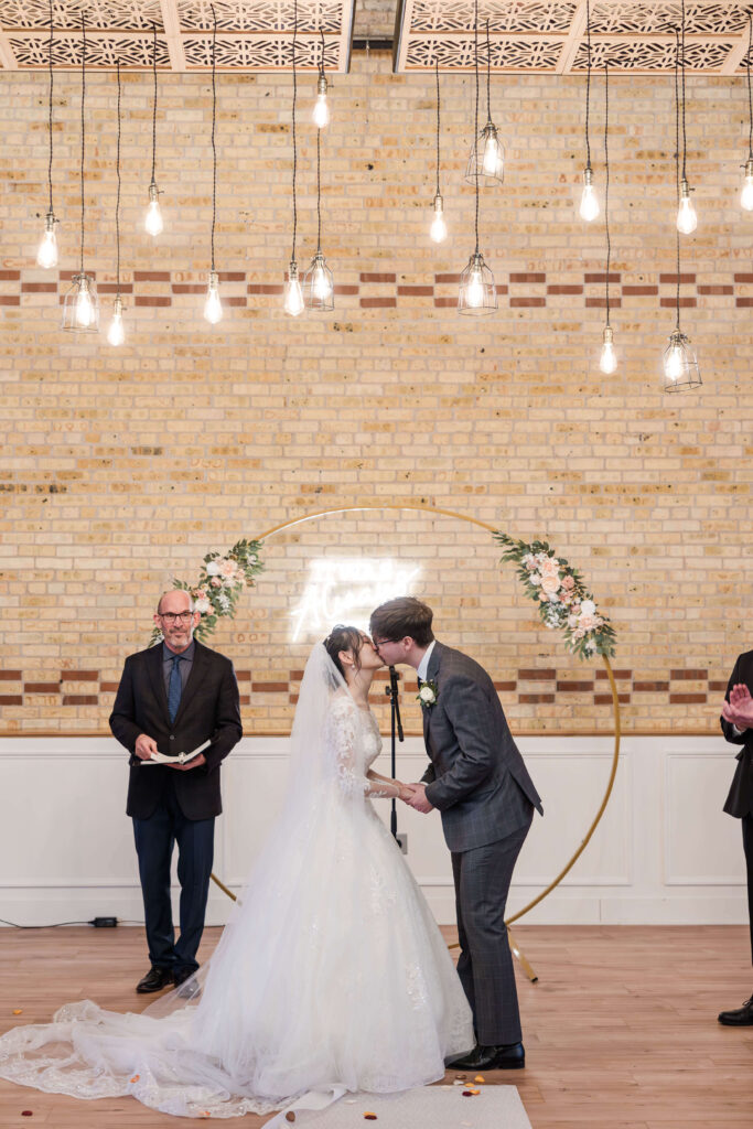 Bride and groom first kiss at wedding ceremony 10 South Venue. 