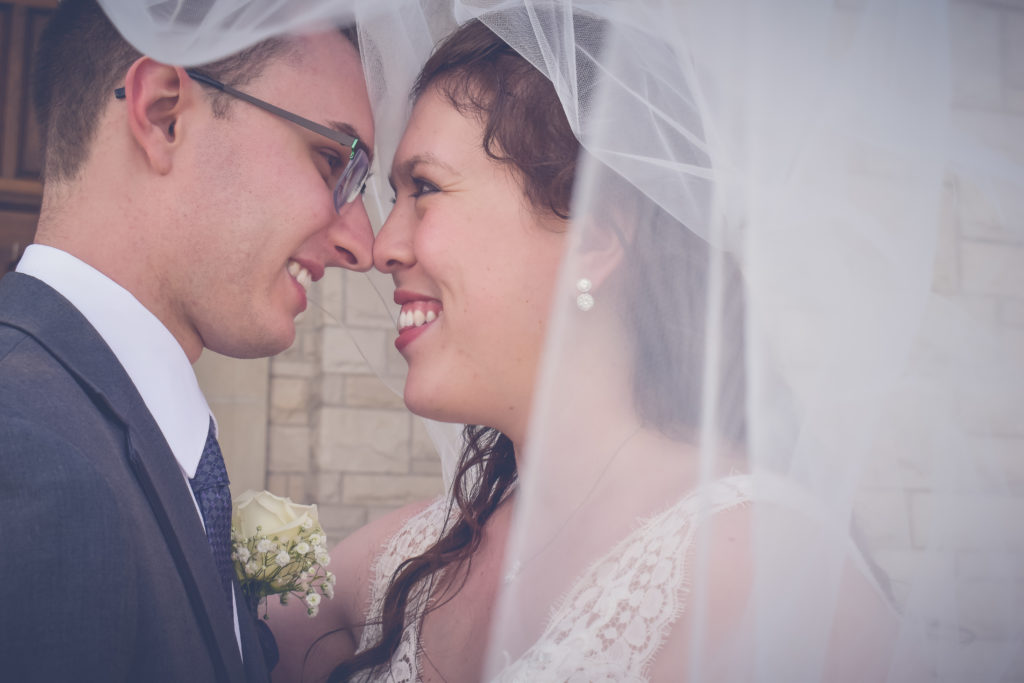 Bride and groom touching nose veil photograph