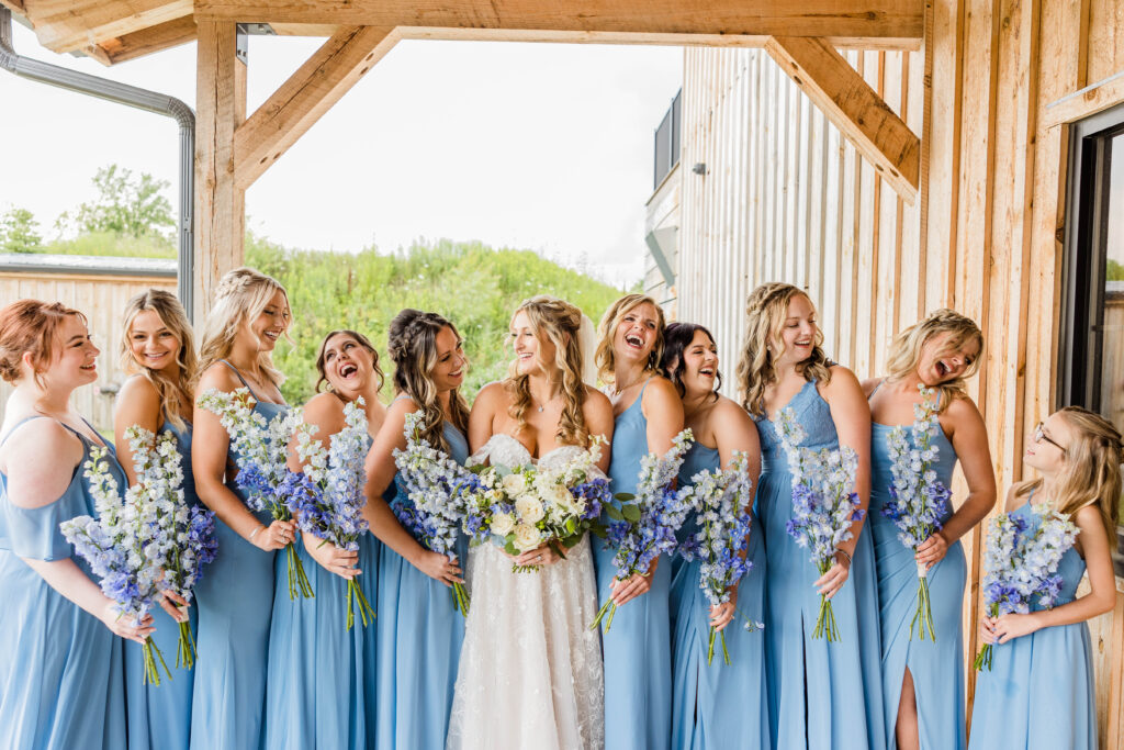 Bride laughing with bridesmaids on wedding day. 