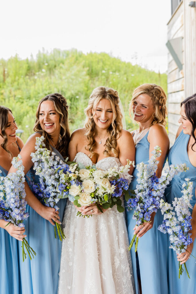Bride laughing with bridesmaids on wedding day. 