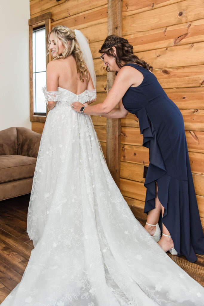 Mother helping bride into wedding dress. 
