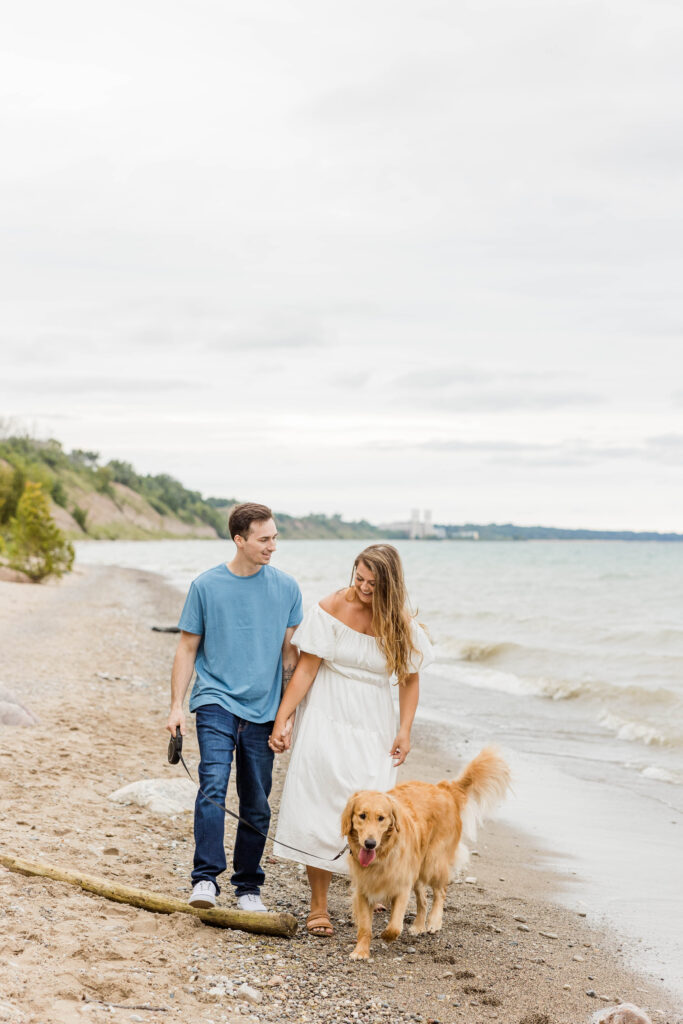 Golden retriever and engaged couple walking on a beach at Lions Den Gorge Nature Preserve, in Wisconsin. 