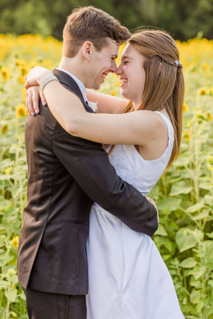 Bride and groom touching noses in a field of sunflowers during golden hour at the Bowery in Wisconsin.