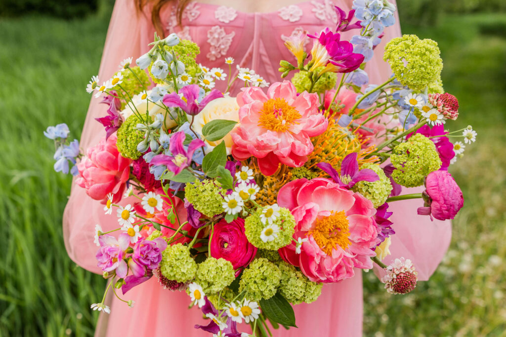 Stunning pink floral bouquet with pops of purple and green designed by Flora Elements with pink ball gown with floral details at Fete of Wales in Wisconsin. 
