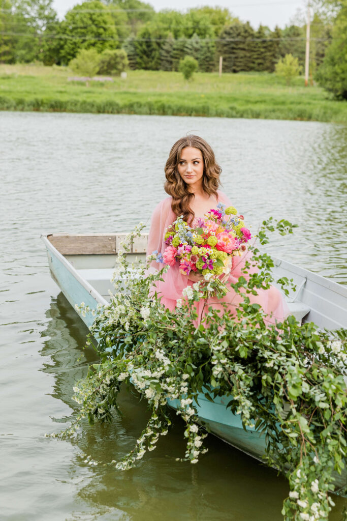 Bride in pink wedding gown in a blue paddle boat on a pond in Waukesha, Wisconsin.